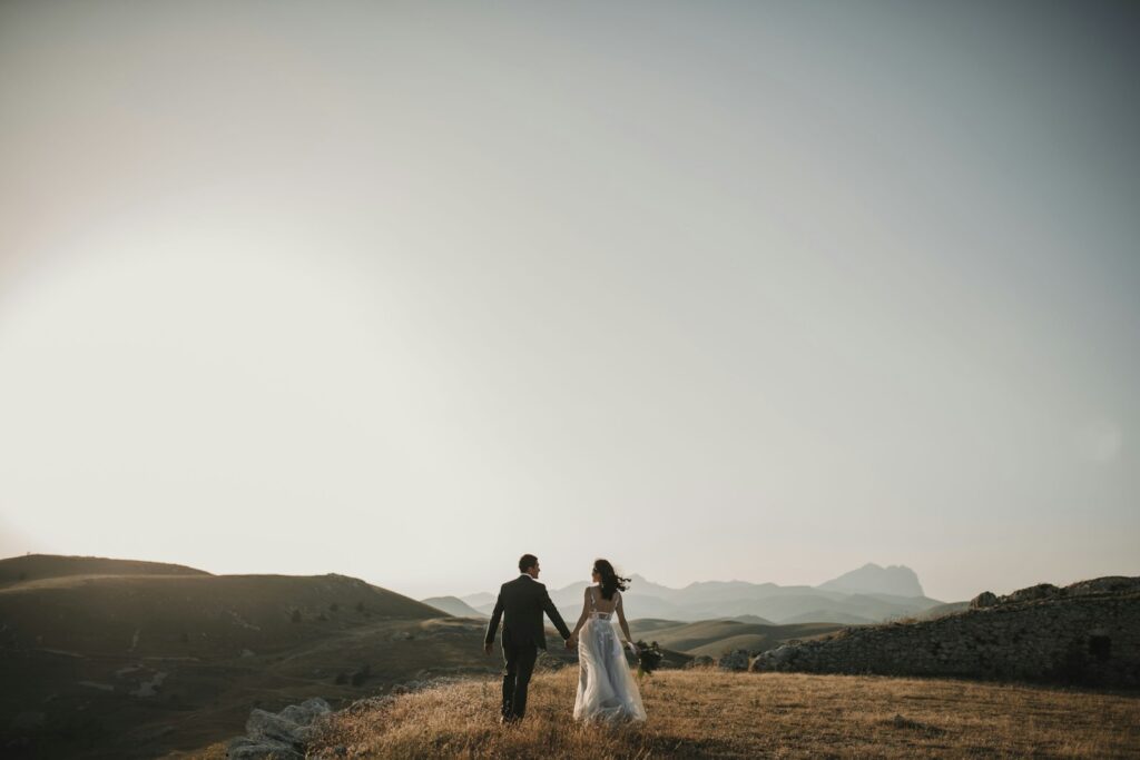 Brautpaar spaziert nach der kleinen Hochzeit über einen grünen Hügel