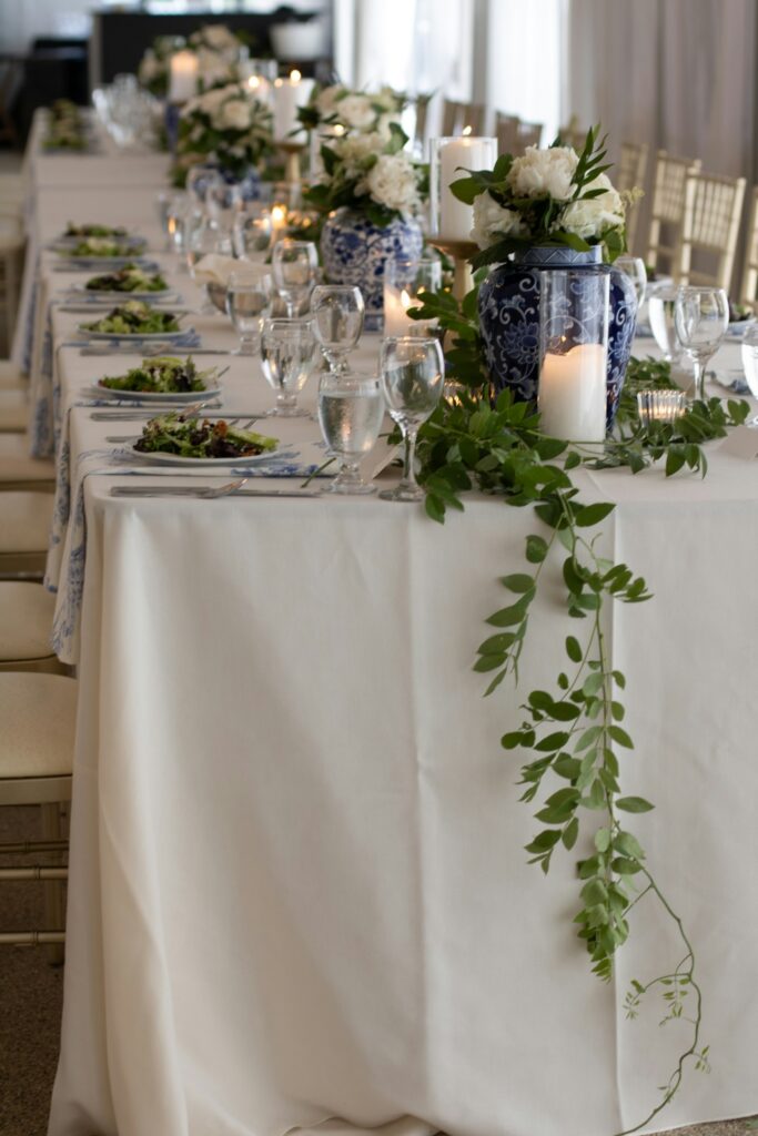 Lange Hochzeitstafel mit weißen und blauen Blumen und frischem Grün
