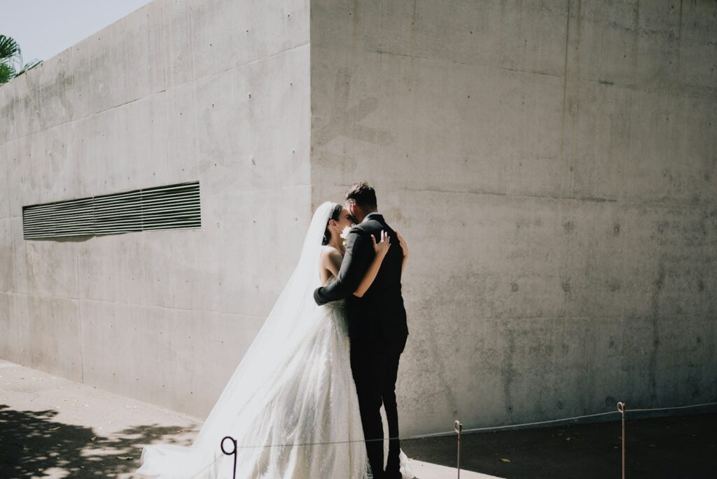 Minimalistische Hochzeit: Brautpaar umarmt sich vor einer schlichten Betonwand