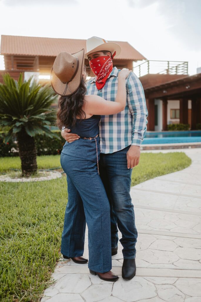Paar mit Cowboyhüten und Jeans umarmt sich im Freien