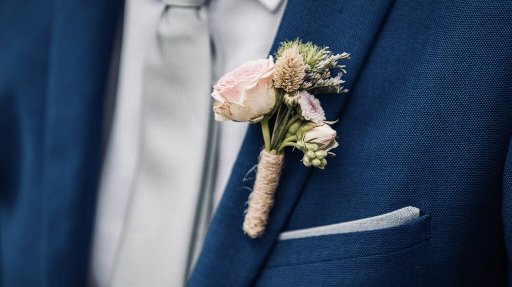 Rosa Rose als Ansteckblume auf einem blauen Sakko