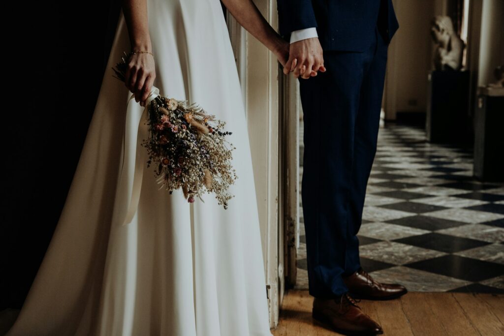 Boho Hochzeit: Braut im weißen Kleid hält einen Strauß aus Trockenblumen