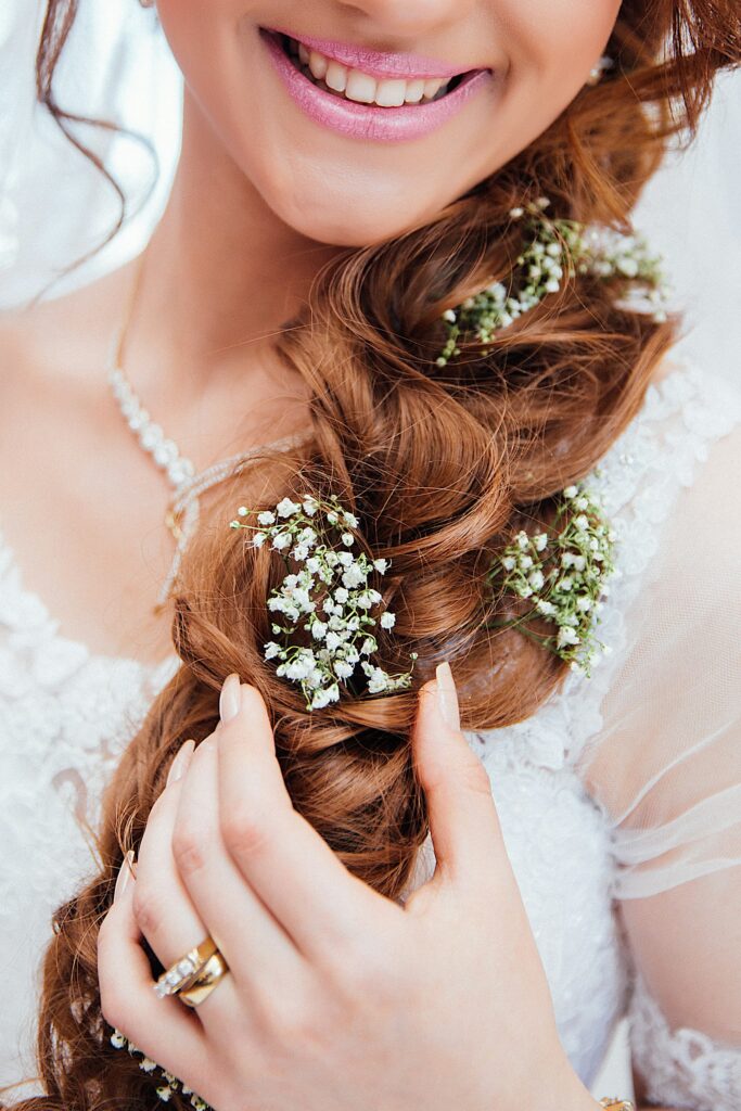Braut hält ihre Haare mit eingesteckter Blüte zur Seite