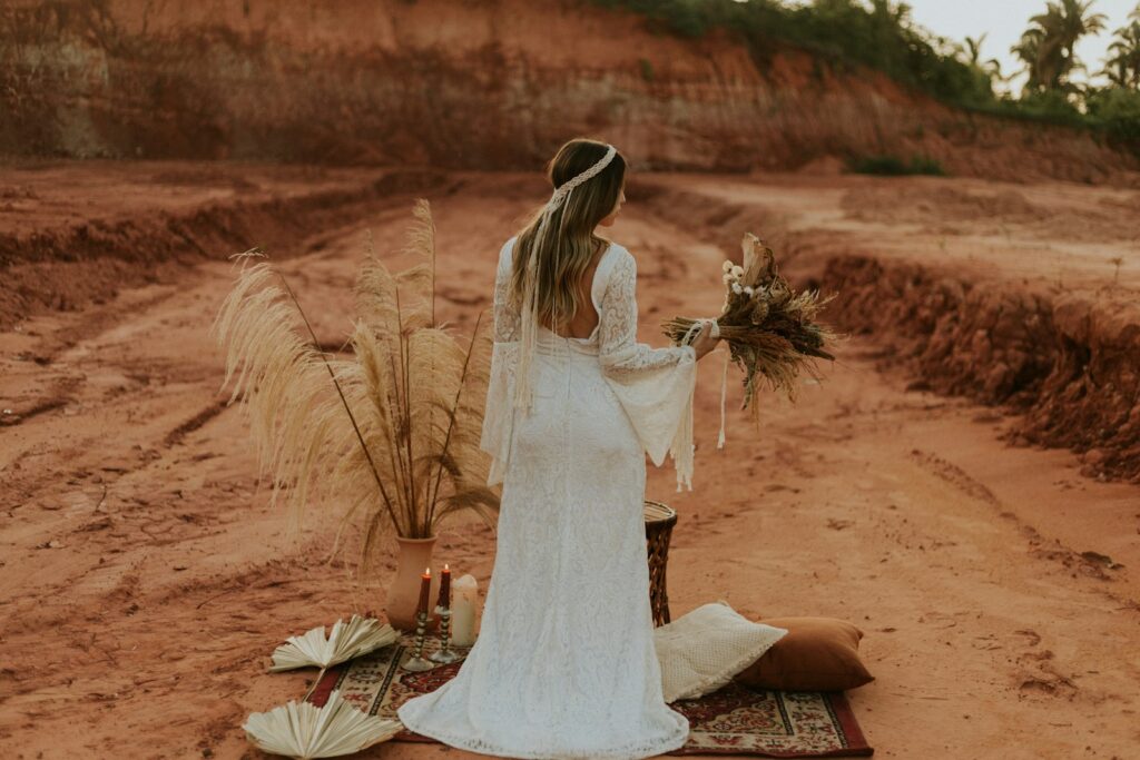 Braut im weißen Hochzeitskleid sitzt am Sandstrand
