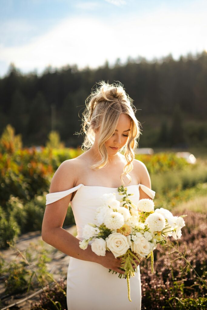 Braut im weißen Kleid hält einen Blumenstrauß in den Händen