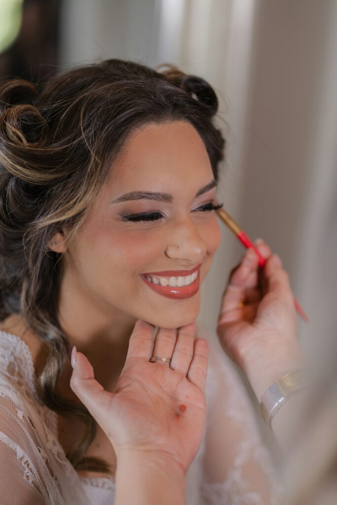 Braut Make-up: Frau trägt mit einem Pinsel Wimpern und Mascara auf