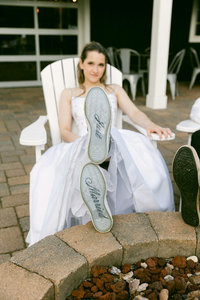 Braut trägt weiße Sneaker mit Just-married-Schriftzug auf der Sohle als bequeme Brautschuhe