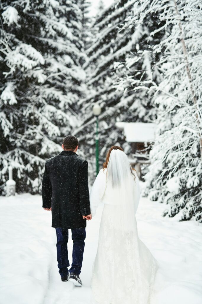 Brautpaar spaziert bei einer Winterhochzeit durch verschneite Landschaft