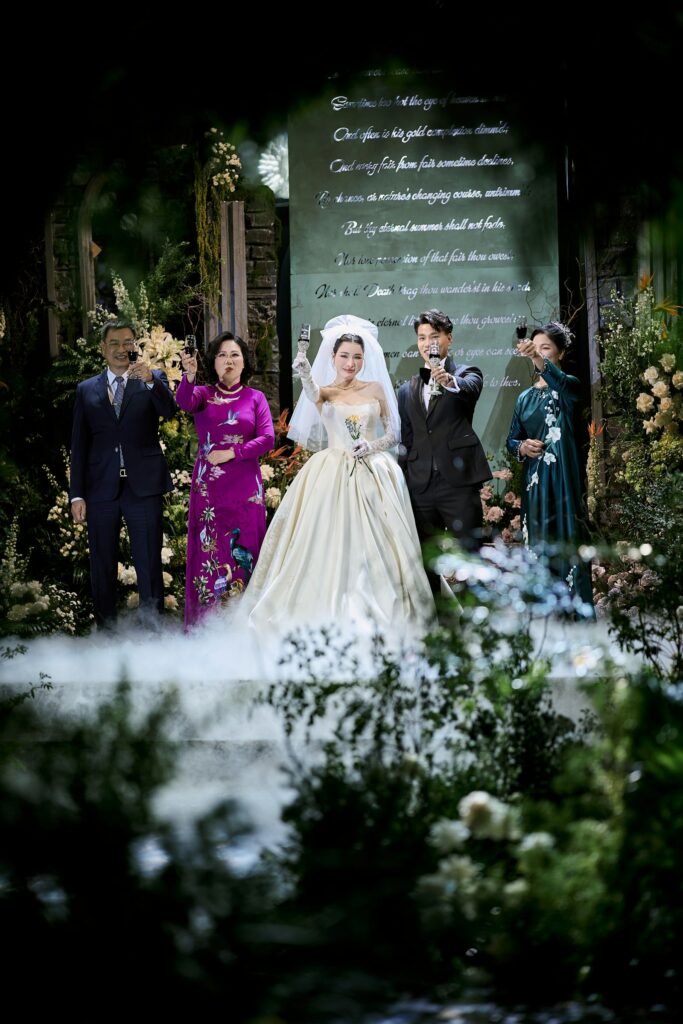 Brautpaar und Gäste stoßen bei einer Hochzeit im Freien mit Gläsern an