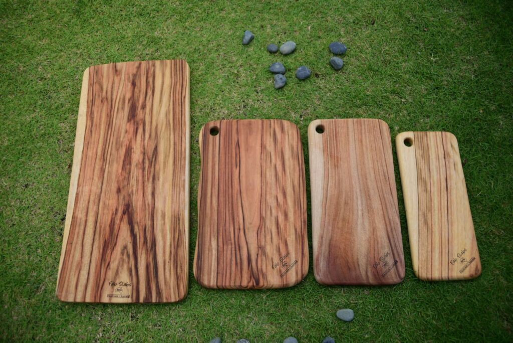 Drei Schneidebretter aus Holz auf einer Wiese, beliebte Basis für personalisierte Hochzeitsgeschenke