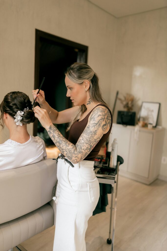 Friseurin steckt einer Frau die Haare zu einer Brautfrisur hoch