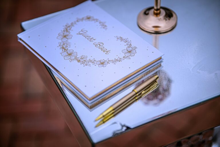 Gästebuch mit goldenem Stift auf verspiegeltem Tisch, Symbolbild für Gästebuch Hochzeit Ideen