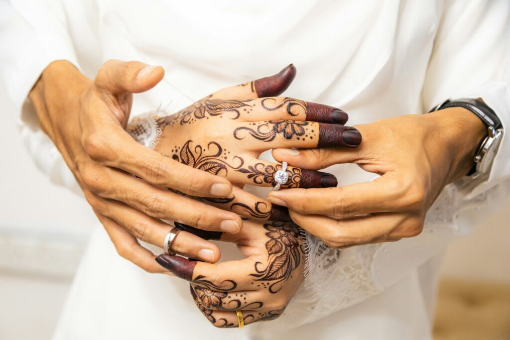Hände mit Henna-Mustern beim Ringtausch während einer Hochzeitszeremonie