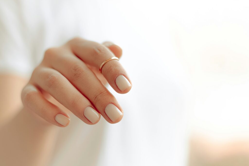 Hand mit weißer, glänzender Maniküre als Inspiration für elegante Hochzeitsnägel