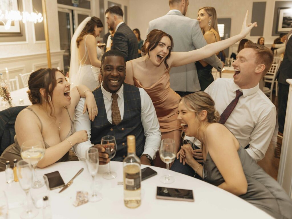 Hochzeitsgäste sitzen gemeinsam an einer weiß eingedeckten Festtafel