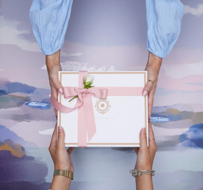 Zwei Hände überreichen ein verpacktes Geschenk