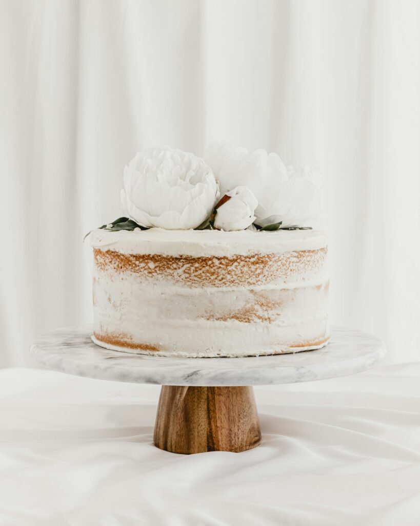 Hochzeitstorte mit weißer Creme und frischen Blüten auf einem Tortenständer