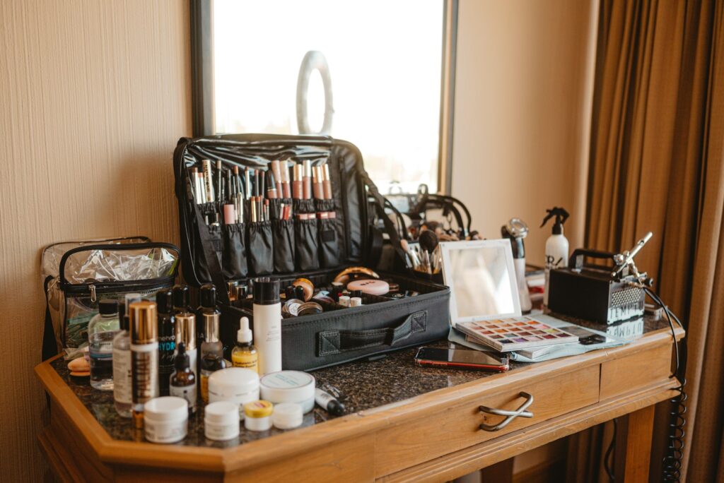Make-up-Koffer einer Visagistin mit Pinseln und Paletten auf einem Holztisch