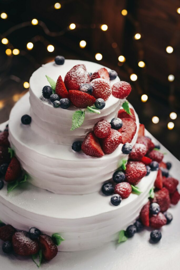 Nahaufnahme einer dreistöckigen Vanilletorte mit Heidelbeeren und Erdbeeren