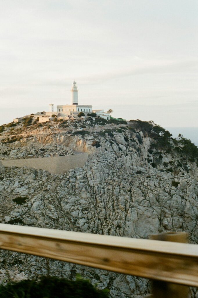 Weißer Leuchtturm auf felsiger Küste über dem Meer