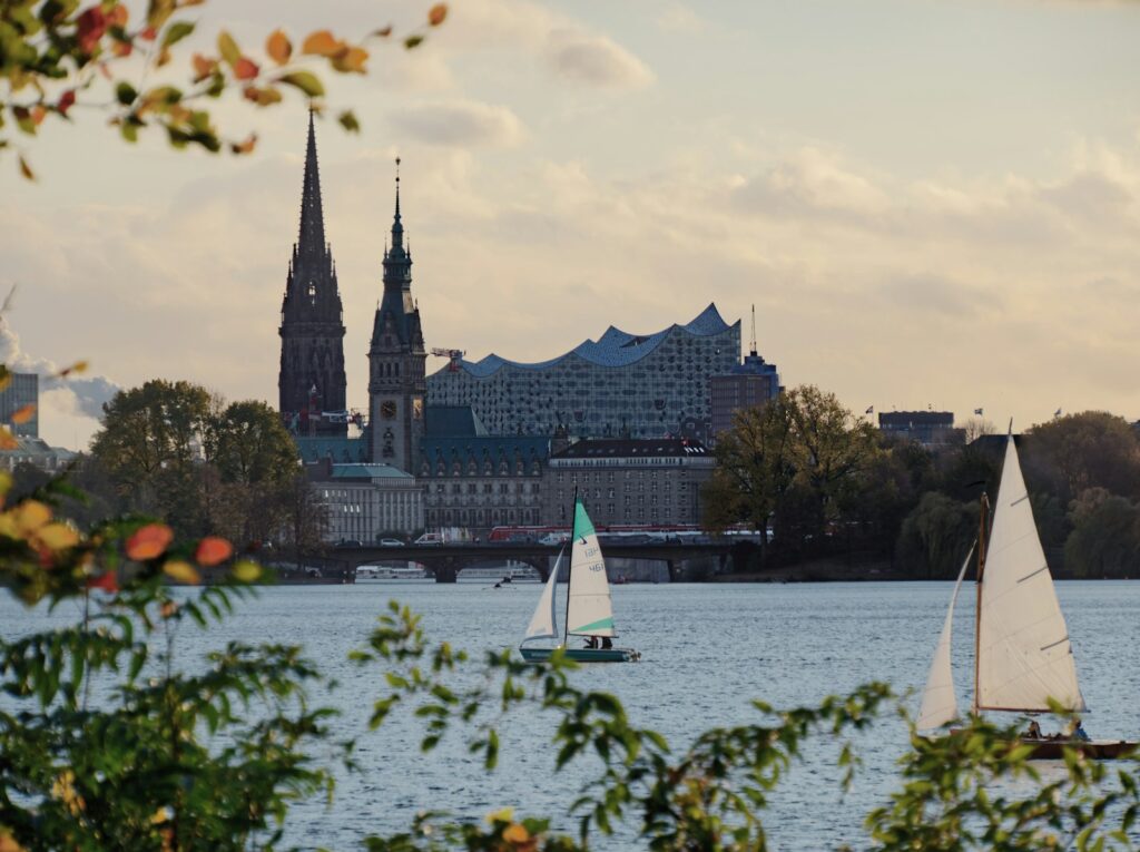 Weißes Segelboot auf dem Wasser vor Stadtgebäuden in Hamburg